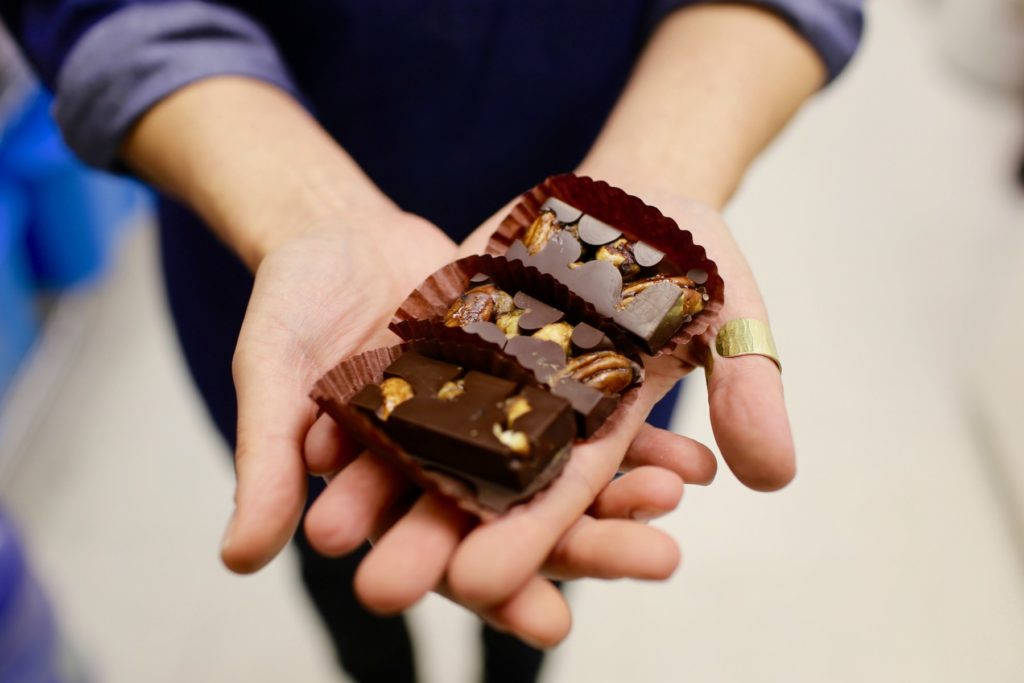 hands holding out chocolates with walnuts