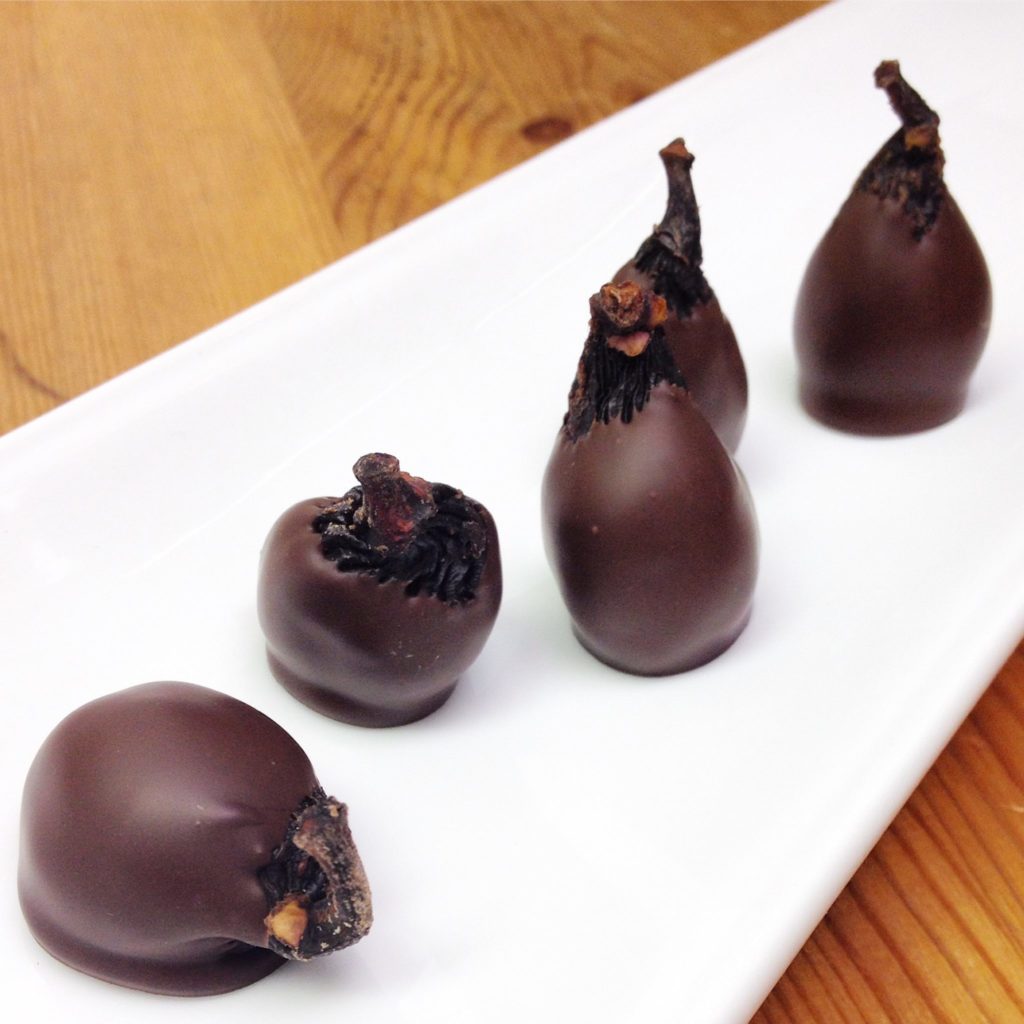 Chocolate dipped figs on a white plate