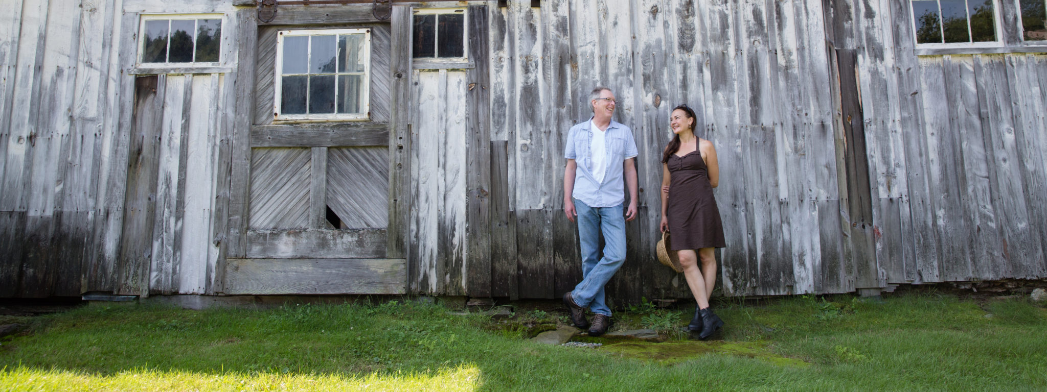 john singer and dar tavernier standing in front of a wooden barn