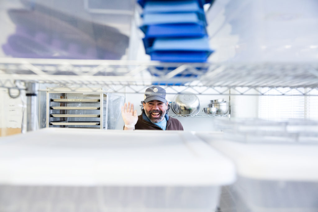 Tavernier Chocolates chocolatier peeks out and waves high in-between shelves of molds