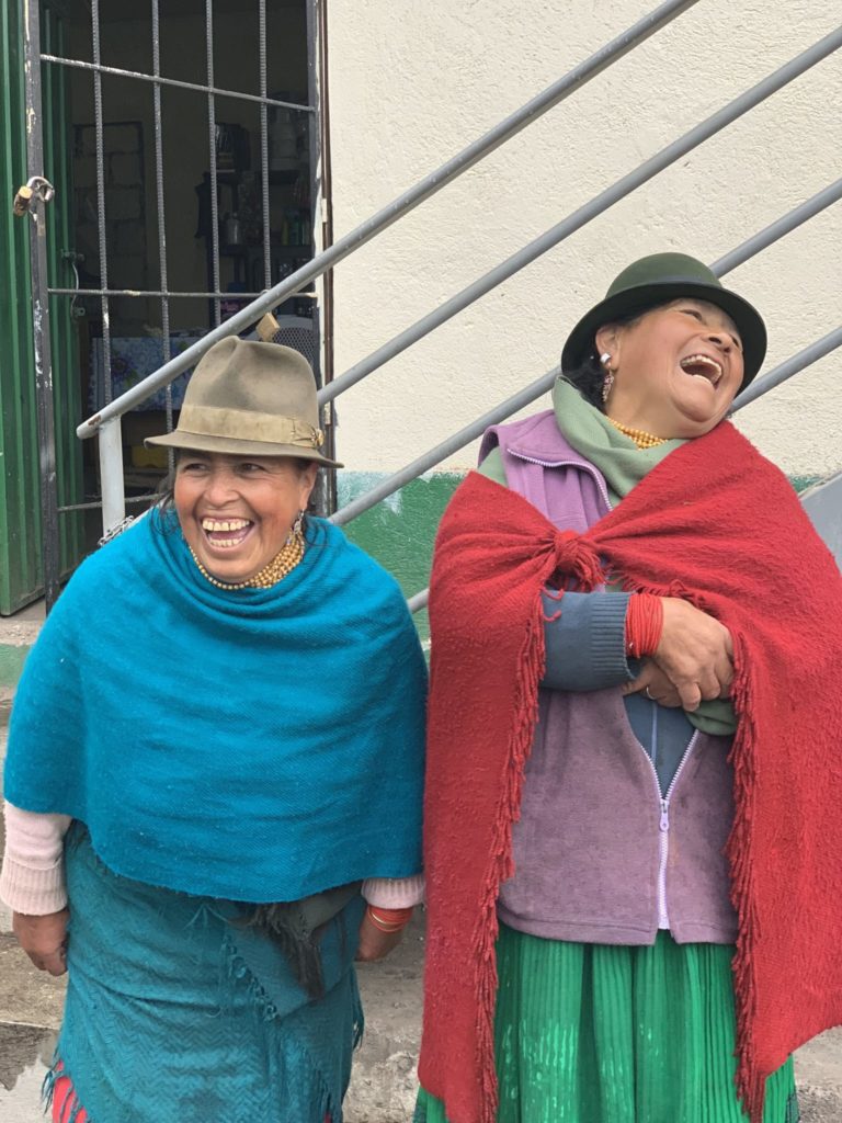 Two Ecuadorian women wearing hats and laughing
