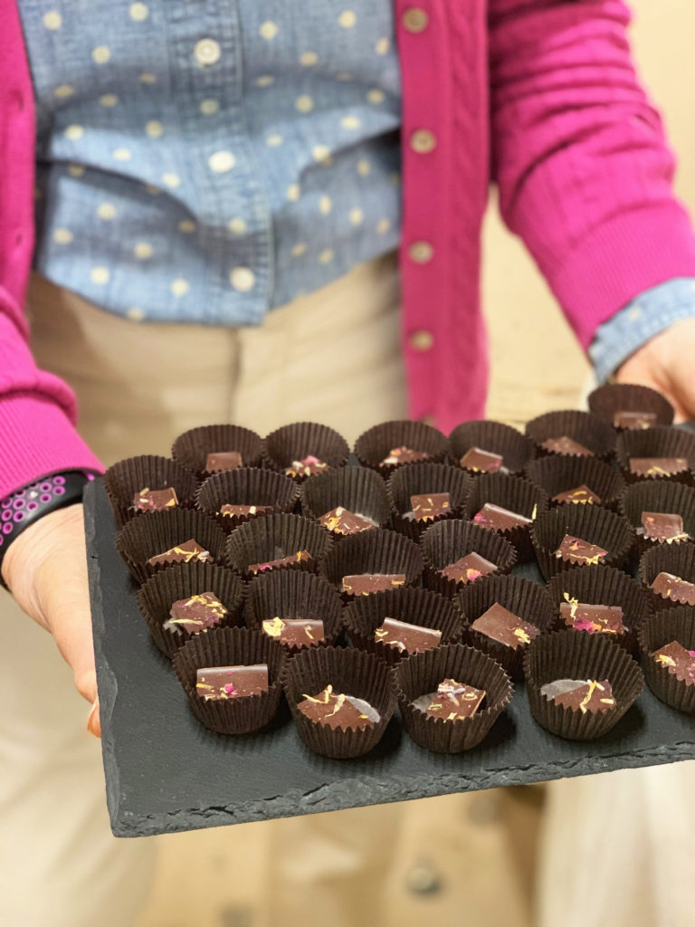 Woman holding a slate platter of Tavernier chocolate bonbons