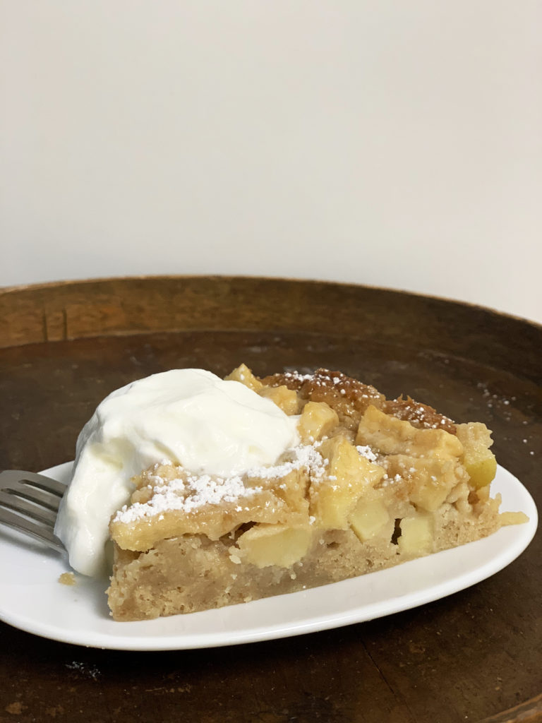 Slice of french apple cake with a chocolate twist and whipped cream