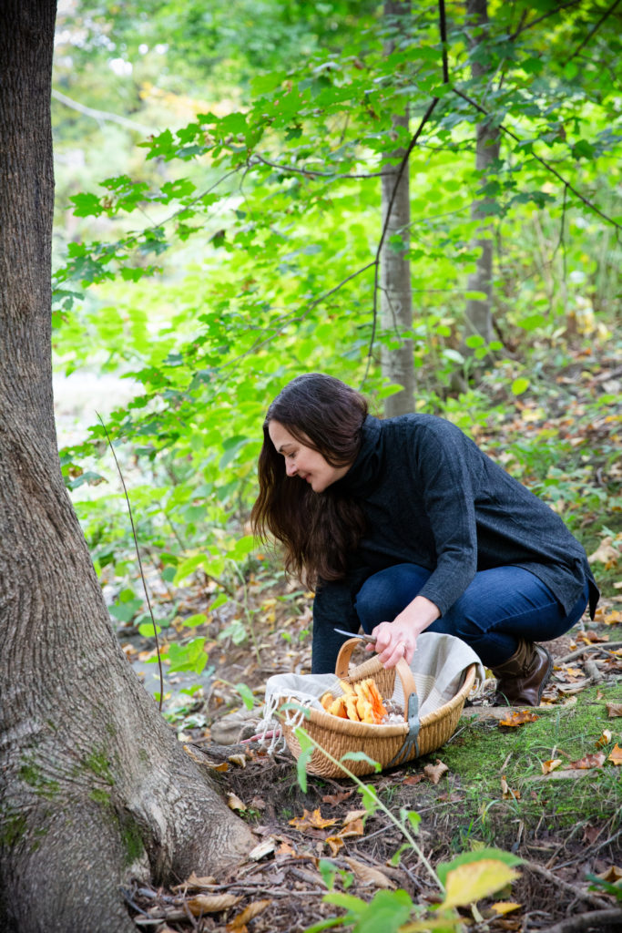 Vermont chocolatier Dar Tavernier-Singer foraging for mushrooms and herbs by an ash tree to make savory chocolate recipes