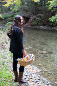 Dar Singer of Tavernier Chocolates standing by a river with a basket of foraged mushrooms