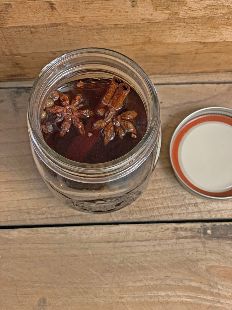 open mason jar filled with cinnamon, star anise, and liquor