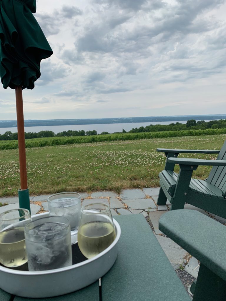 Platter of wine and water in front of a view of the lake in New York wine country