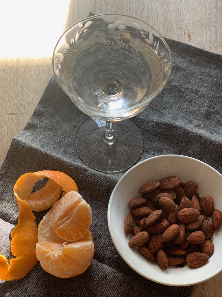 Freshed peeled orange slices, a bowl of spiced almonds and champagne