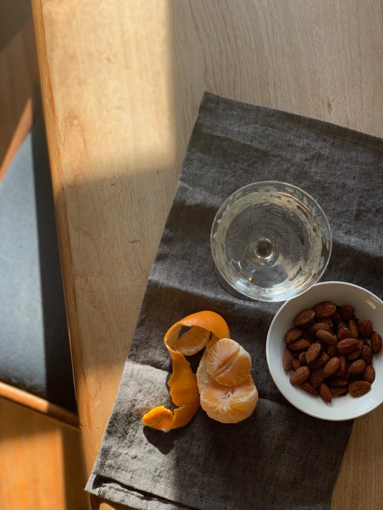 Freshed peeled orange slices, a bowl of almonds and champagne