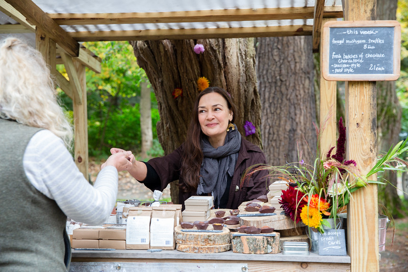 Dar Singer handing chocolates to a customer at her Brattleboro Vermont Farmers Market stand