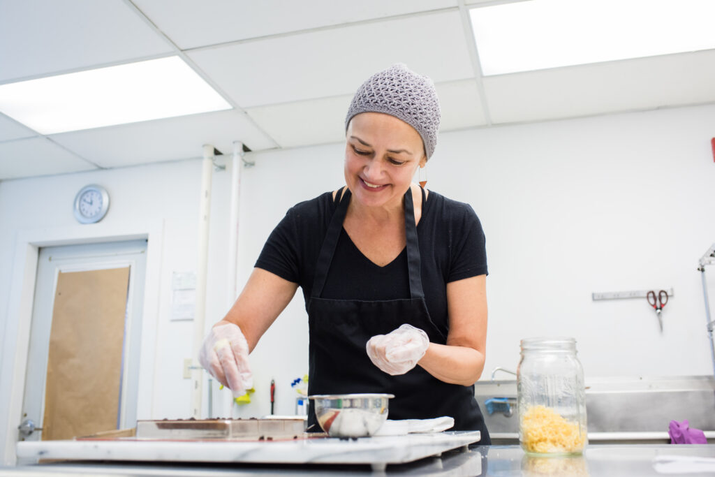 Dar Singer smiling as she makes chocolate in her workshop