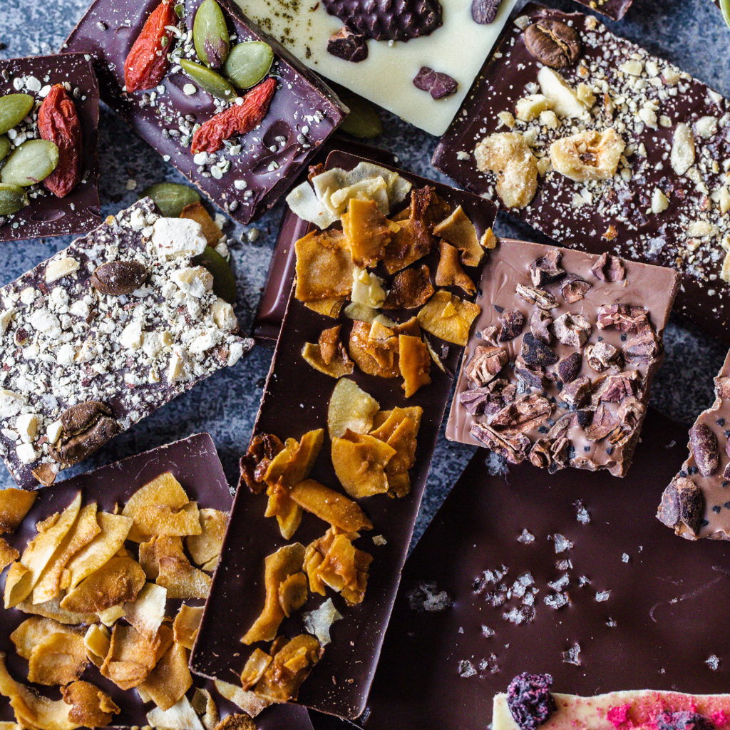 dark, milk and white chocolate bars in a jumbled pile on a stone background