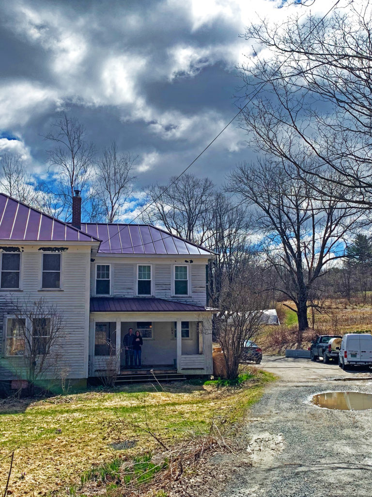 Exterior of Deeridge Farm, which is an old white building with a tin roof