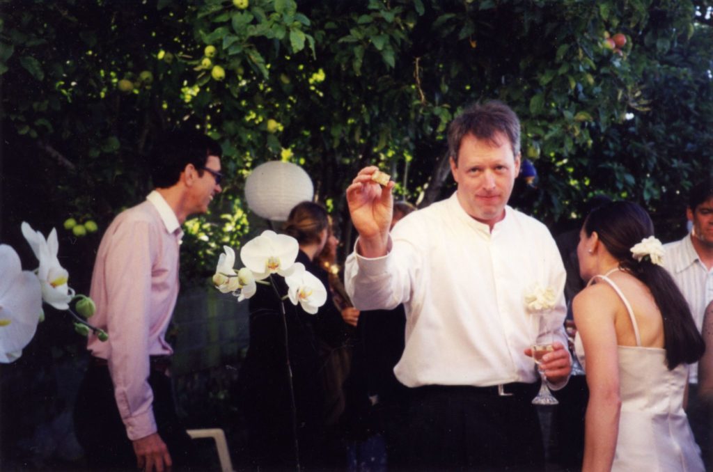 John Singer holding up a cork at his wedding to Dar