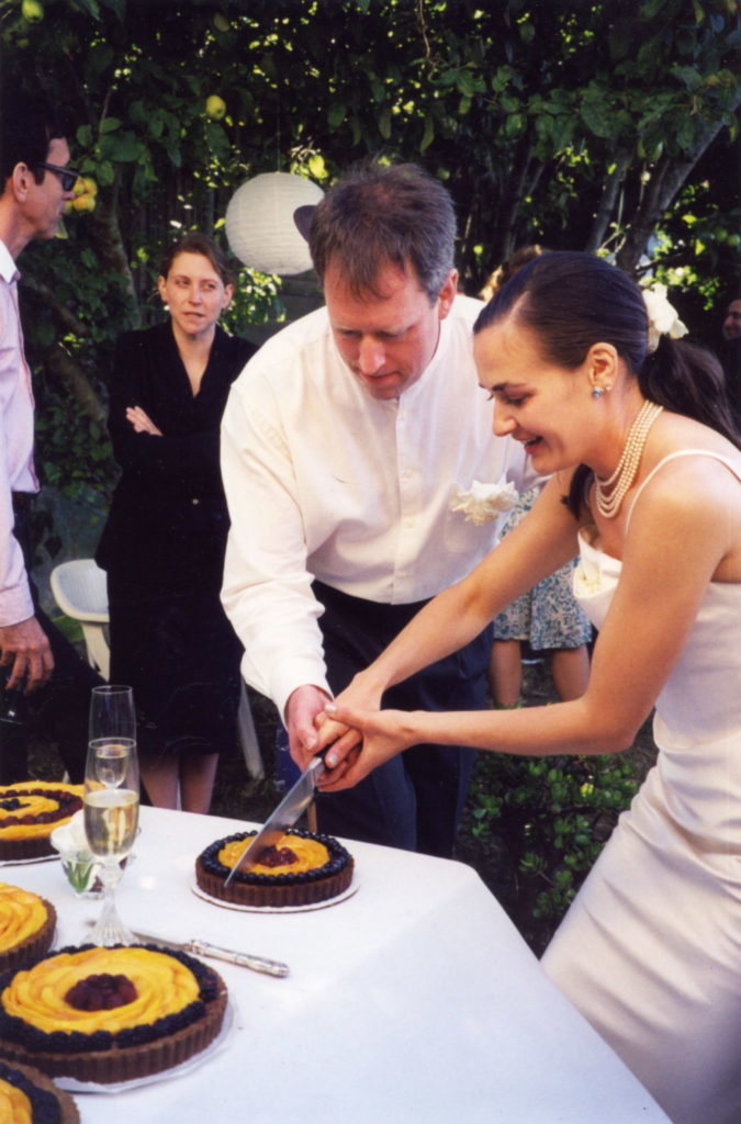 Dar and John Singer cutting a fruit tart on their wedding day