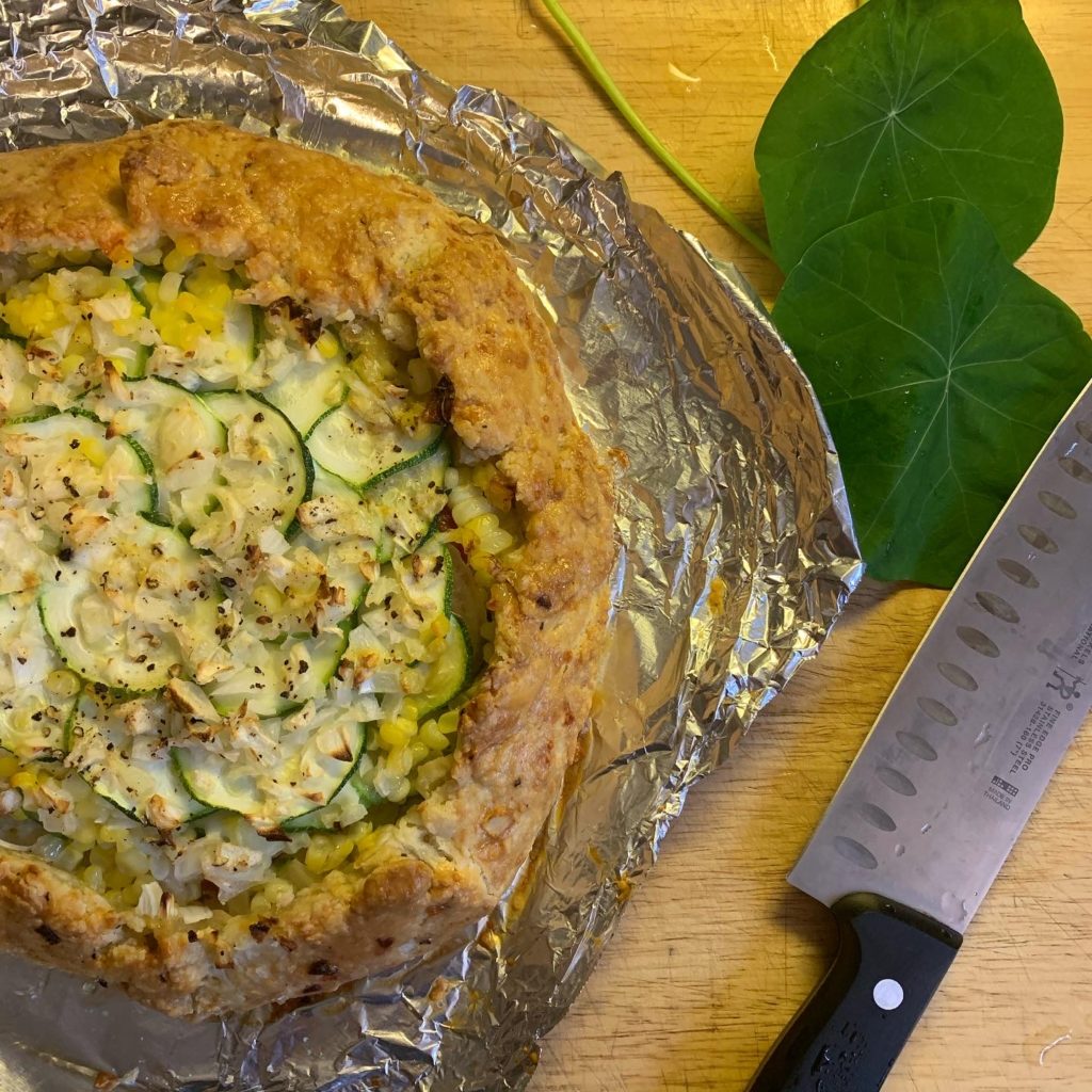 Mole Zucchini Galette sitting on top of foil with a kitchen knife 