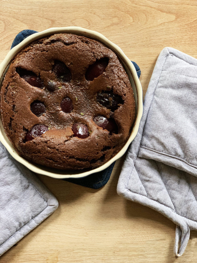 Baked plum clafoutis with balsamic, cocoa, and thyme in a baking dish