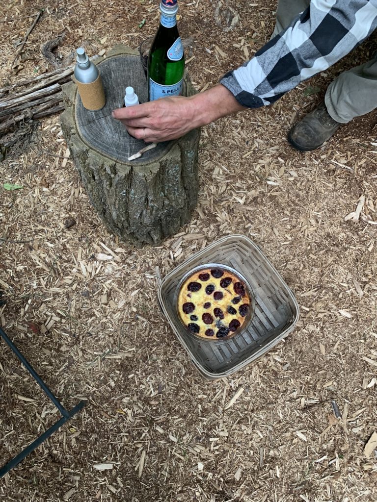 Finished plum clafoutis in a basket on the ground for an outdoor dinner.