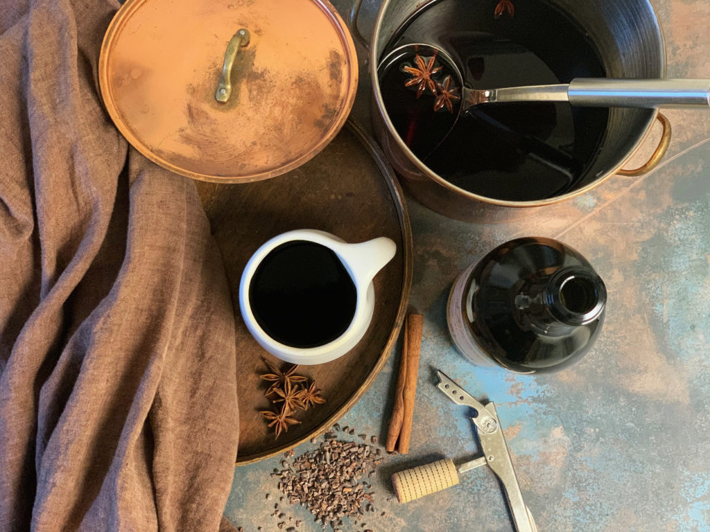 Mulled red wine with spices and chocolate, viewed from above in a copper pot with a mug and brown linen cloth, by Vermont chocolatiers Tavernier Chocolates.