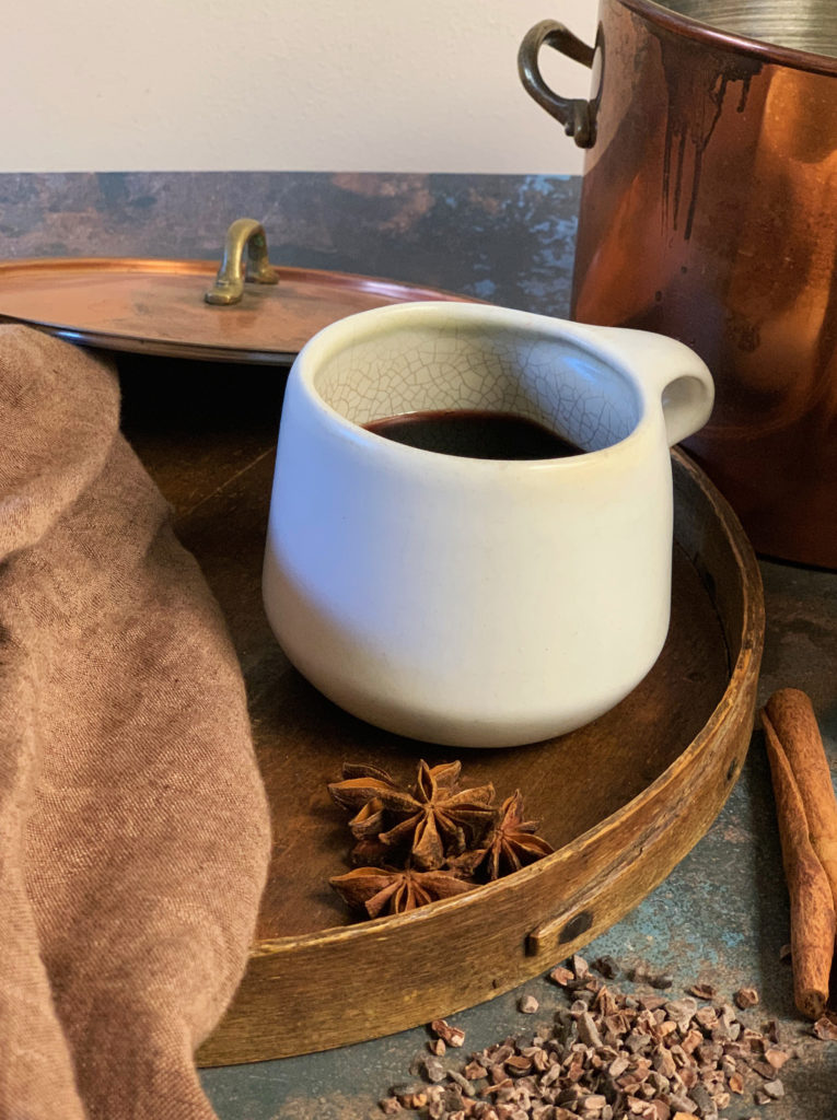 Mulled red wine with star anise and a cinnamon stick in a curvy white mug by Tavernier Chocolates 