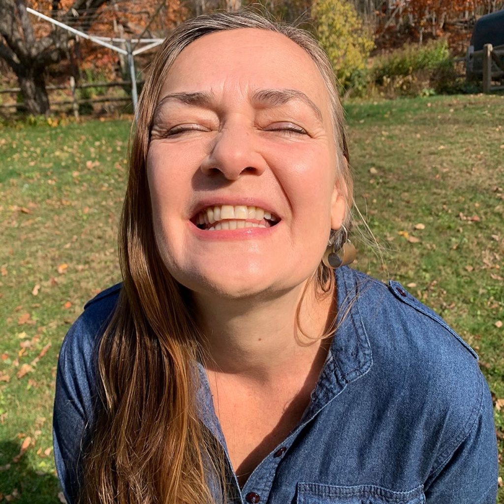 Close up of Dar Singer smiling with her eyes closed. Dar is wearing a blue jean shirt