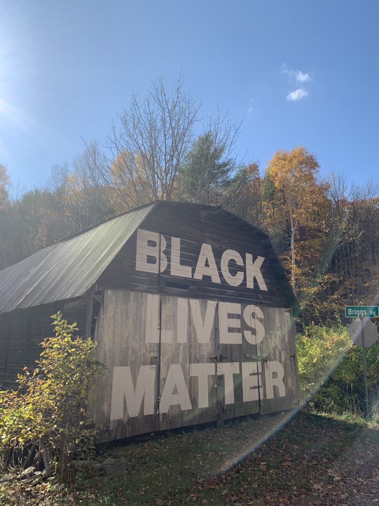 Large wooden barn with a wooden roof. On the side of the barn in huge white letters, reads Black Lives Matter
