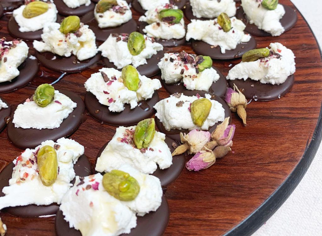 A canapés of Tavernier chocolate topped with chèvre, rose petal, and a pistachio. 