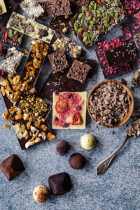 Bars, bonbons and drinking chocolate mix on a stone table top with a silver spoon