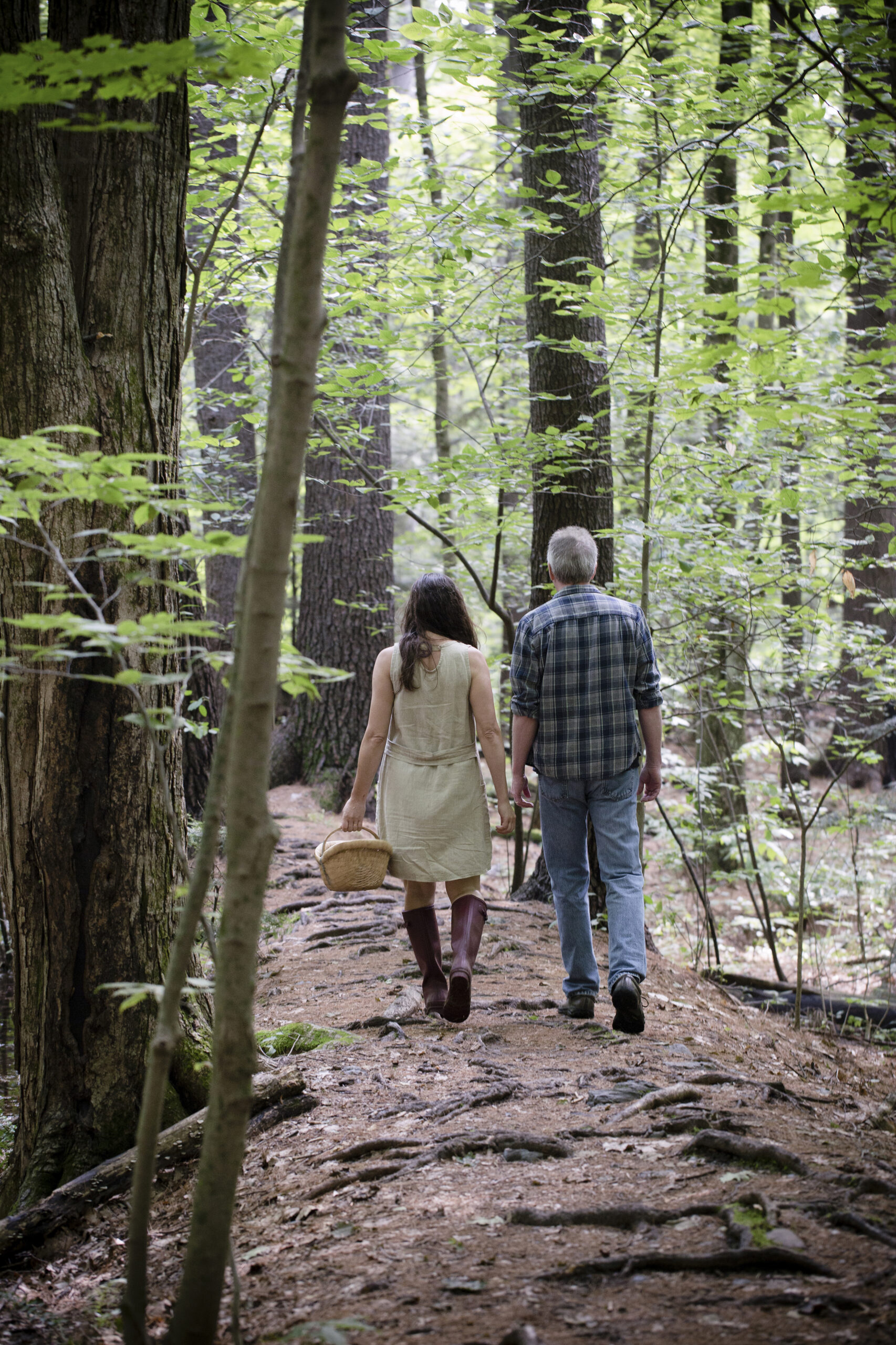 Dar and John walking down a forest path with a basket in Vermont